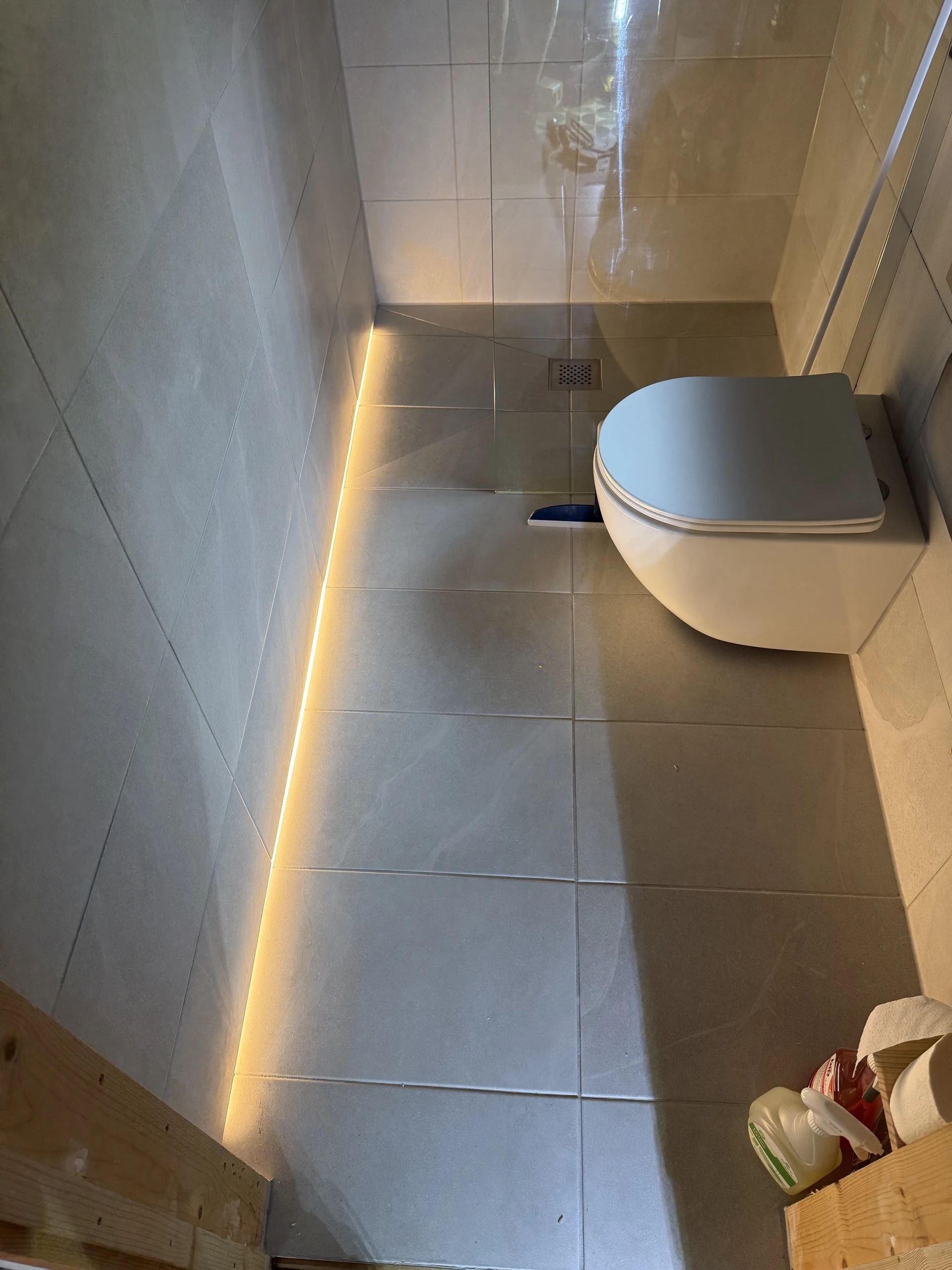 Low-level LED lighting beside a tiled bathroom floor